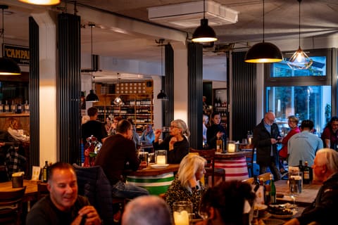 Voll besetztes Restaurant Errante in Worms am Abend, Gäste an Holztischen unter warmem Licht