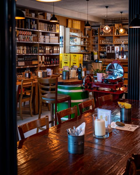 Restaurant Errante mit Holztischen, Kerzenlicht und Feinkostregalen im Hintergrund